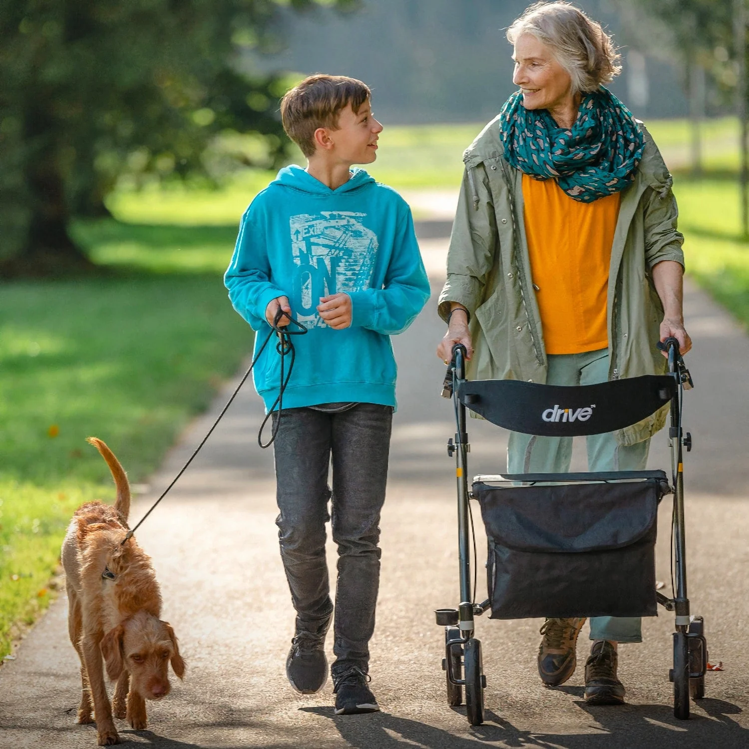 Older woman using a Drive Nitro SL rollator walker outdoors with grandson and dog