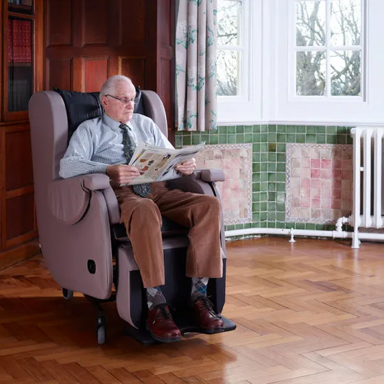 Man reading a newspaper in a tilt-in-space chair at home